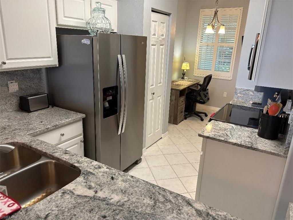 Kitchen featuring light granite counters, pendant lighting, backsplash, and an office area.