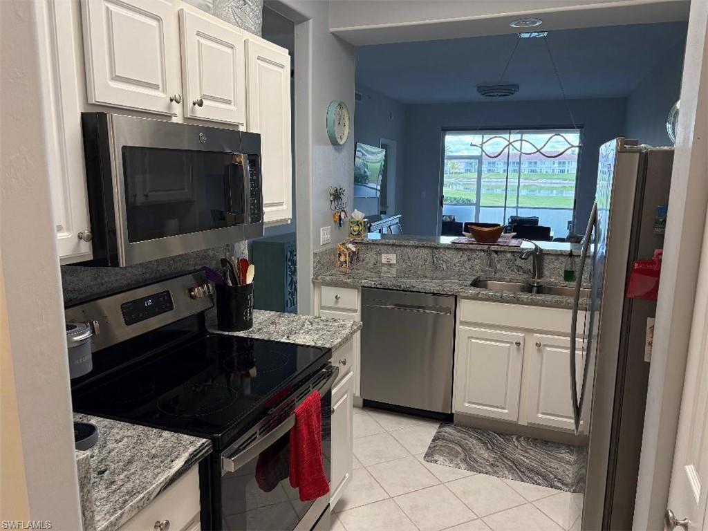 Kitchen with stainless steel appliances, white cabinets and granite counters.