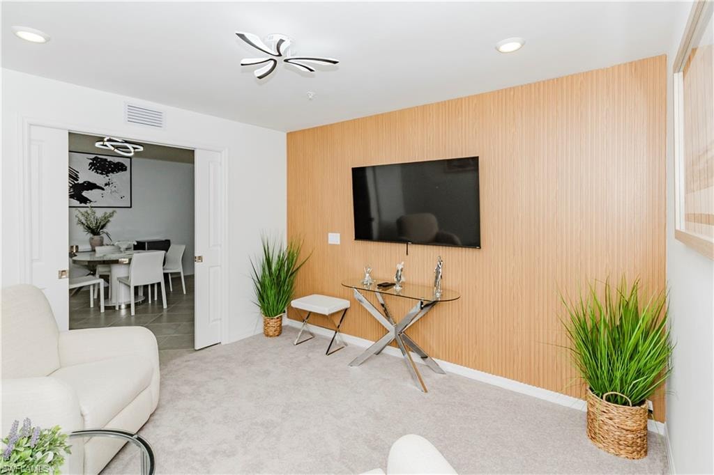 Living room featuring an accent wall, carpet, baseboards, and recessed lighting