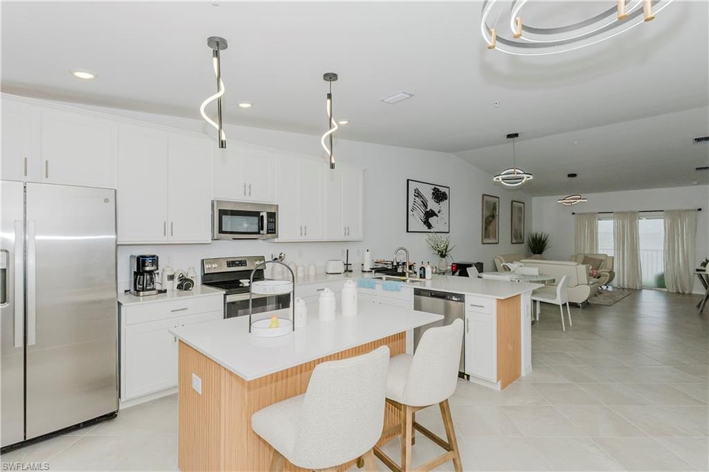 Kitchen featuring appliances with stainless steel finishes, a peninsula, a sink, light countertops, and open floor plan