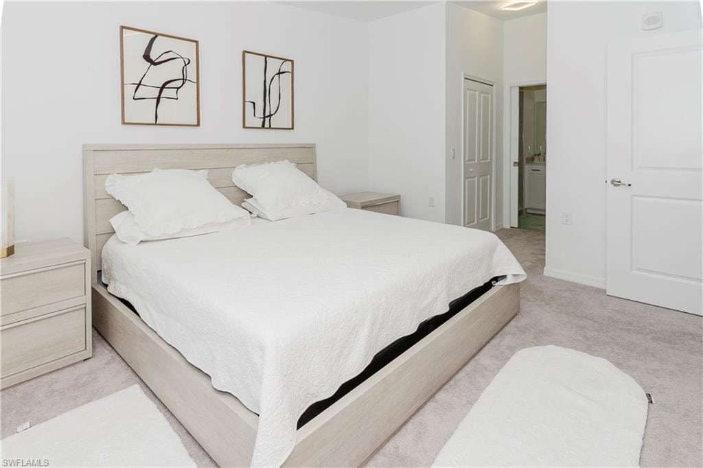 Bedroom featuring light colored carpet and ensuite bath