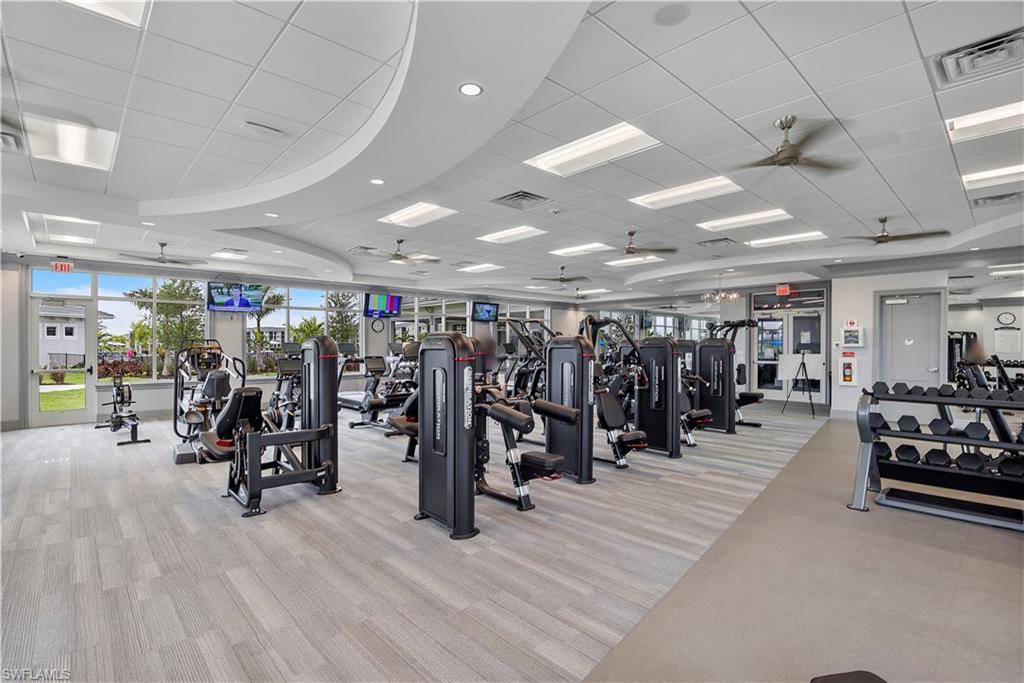 Exercise room with a ceiling fan, light carpet, and a paneled ceiling