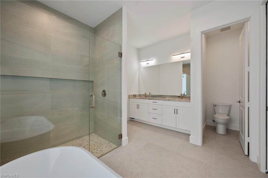 Bathroom with a shower stall, double vanity, and a soaking tub
