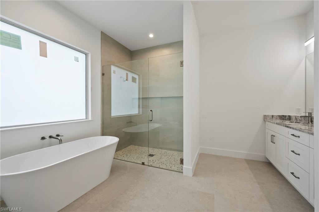 Full bathroom with a shower stall, vanity, a freestanding bath, and recessed lighting