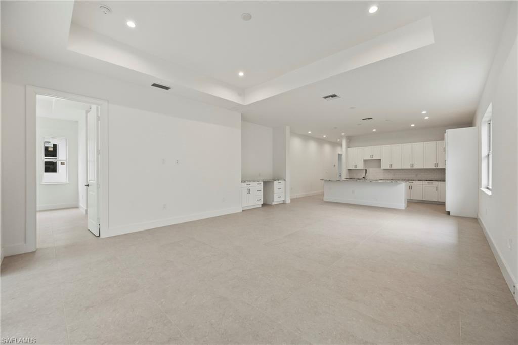 Unfurnished living room featuring recessed lighting and a tray ceiling