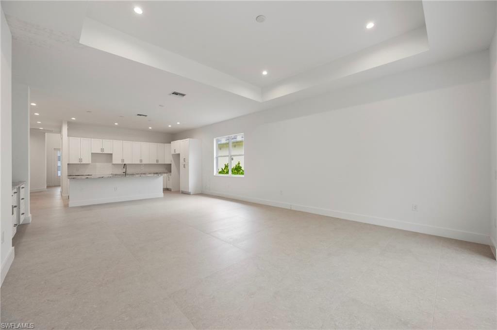 Unfurnished living room with recessed lighting, a tray ceiling, and light flooring