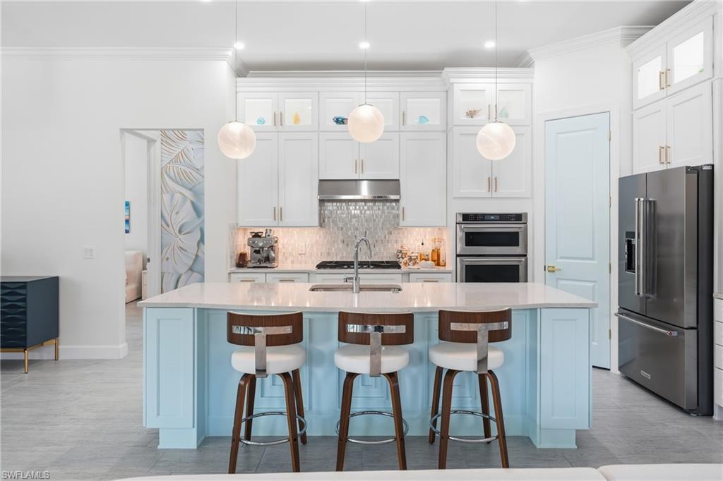 Light-filled kitchen designed for both style and function, featuring freshly painted cabinetry, an updated island with bar seating, and contemporary lighting. The open design creates a natural hub for entertaining while maintaining a sleek, move-in-ready feel.