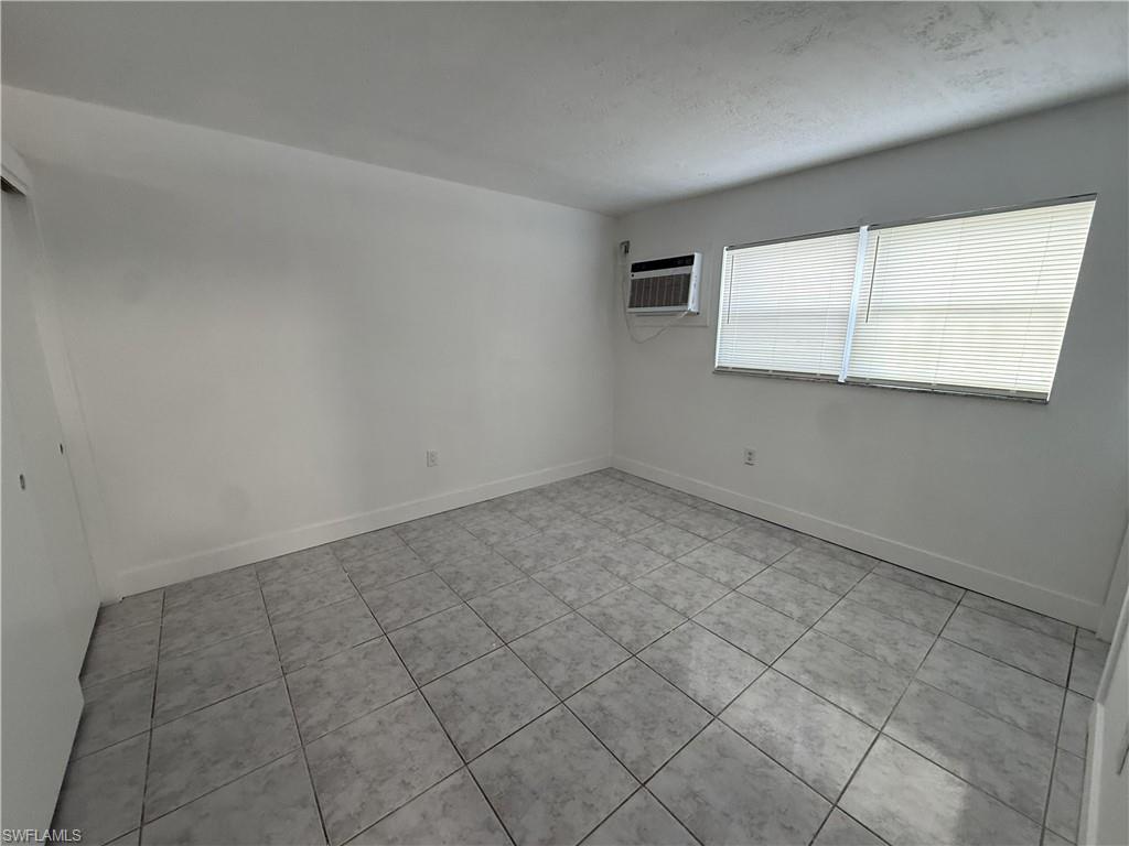 This room features white walls, tiled flooring, and a window with blinds