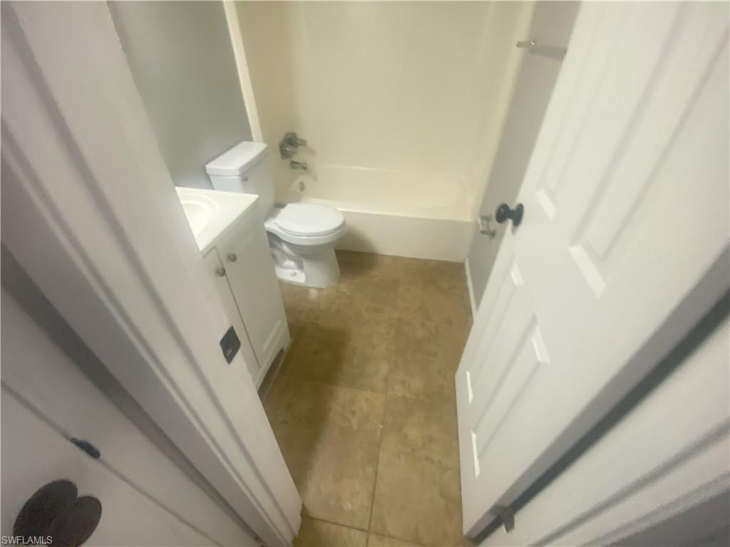 Bathroom featuring vanity, washtub / shower combination, and light tile patterned flooring