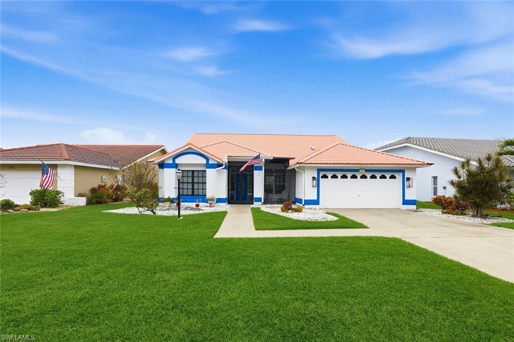 Ranch-style house with a front yard, concrete driveway, a tile roof, a garage, and stucco siding