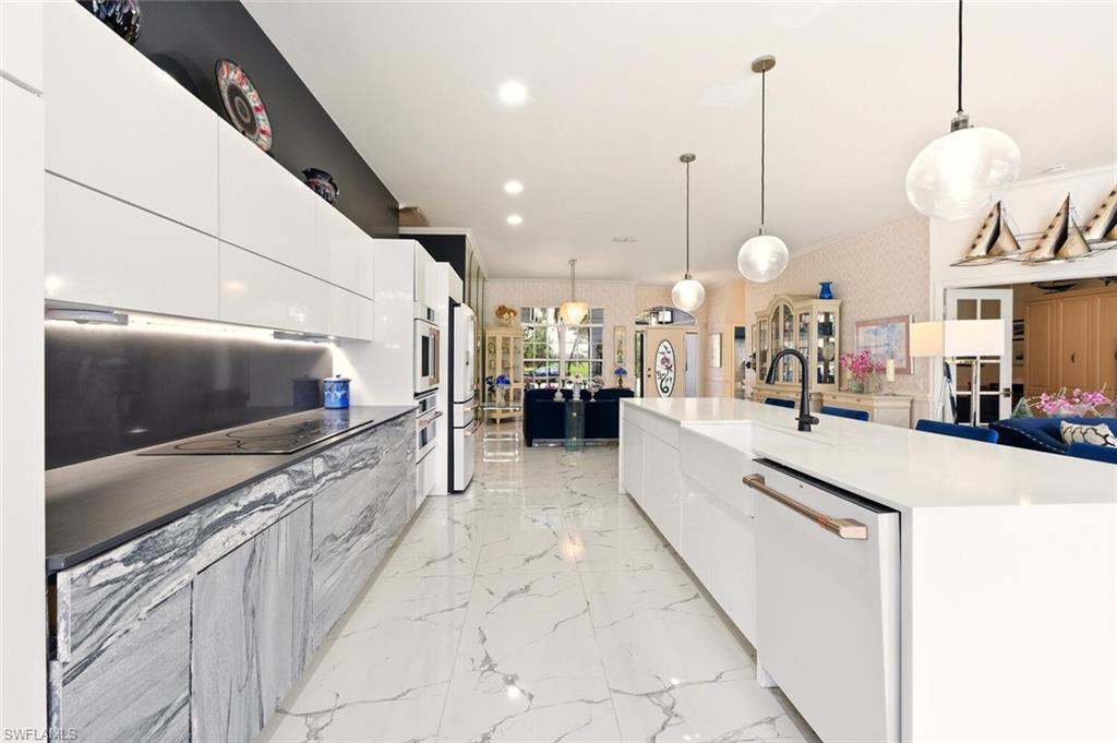 Two tone kitchen featuring modern cabinets, hanging light fixtures, white appliances, wallpapered walls, and two tone cabinets