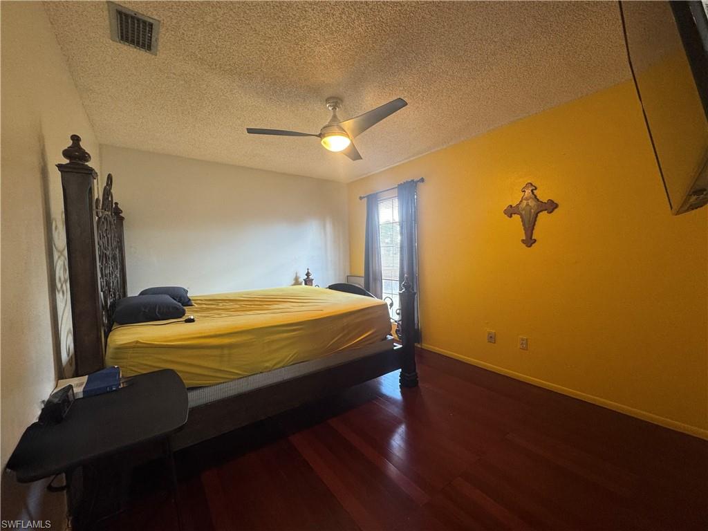 Bedroom with dark wood-style floors, a textured ceiling, and ceiling fan