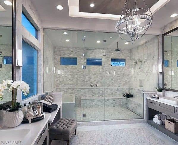 Photos are of a similar home by builder and are for illustrative purposes only. Bathroom with vanity, a stall shower, recessed lighting, tile walls, and a chandelier.