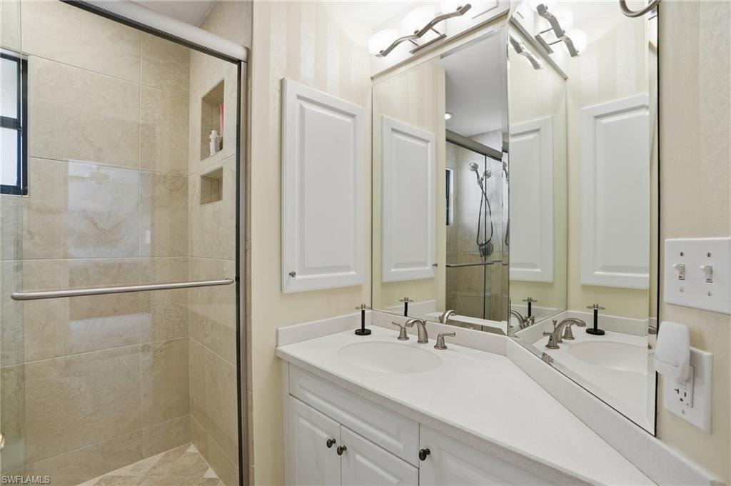 Full bathroom with a shower stall, double vanity, and wallpapered walls