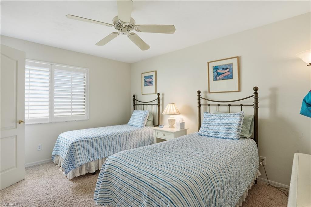 Carpeted bedroom with a ceiling fan and baseboards