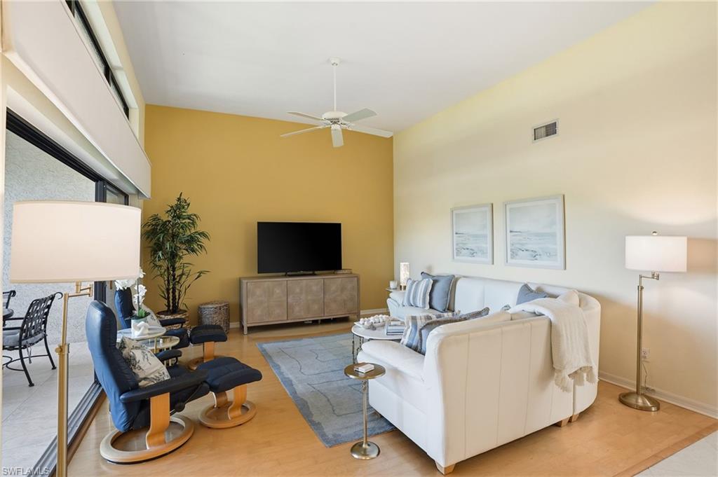 Living room with light wood finished floors, a ceiling fan, and a high ceiling