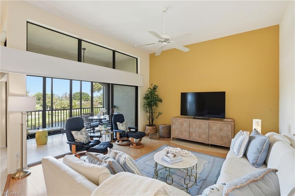 Living area with wood finished floors, a ceiling fan, and a high ceiling