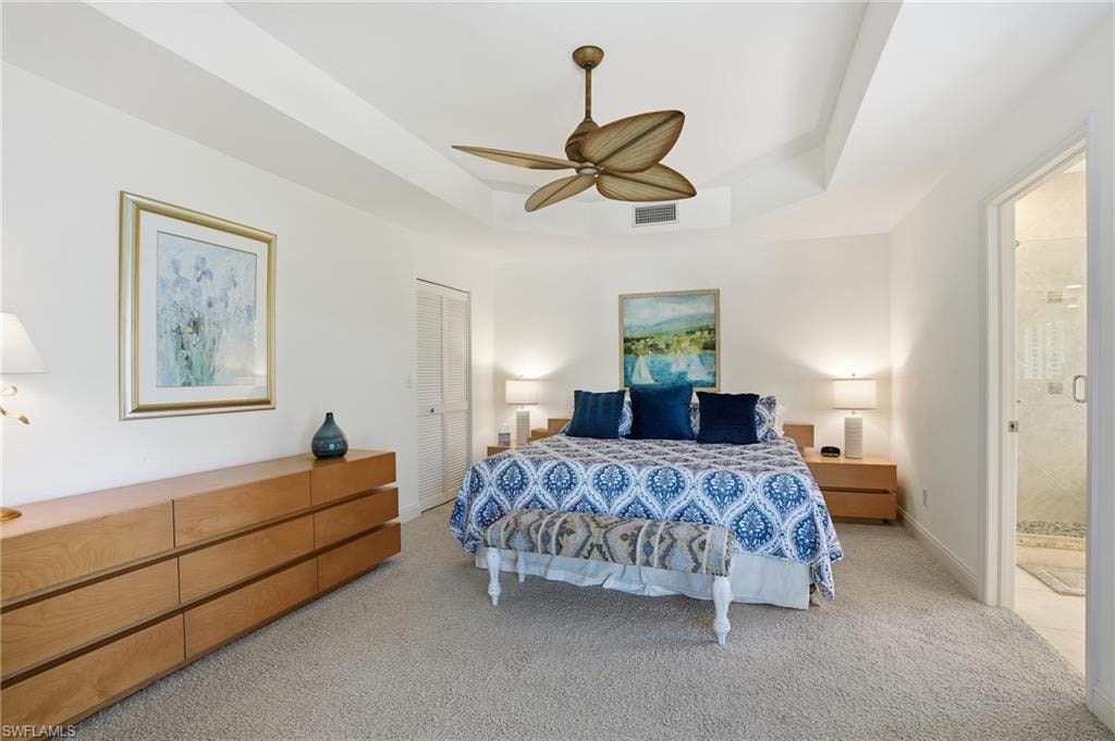 Bedroom with carpet floors, a tray ceiling, a ceiling fan, and a closet