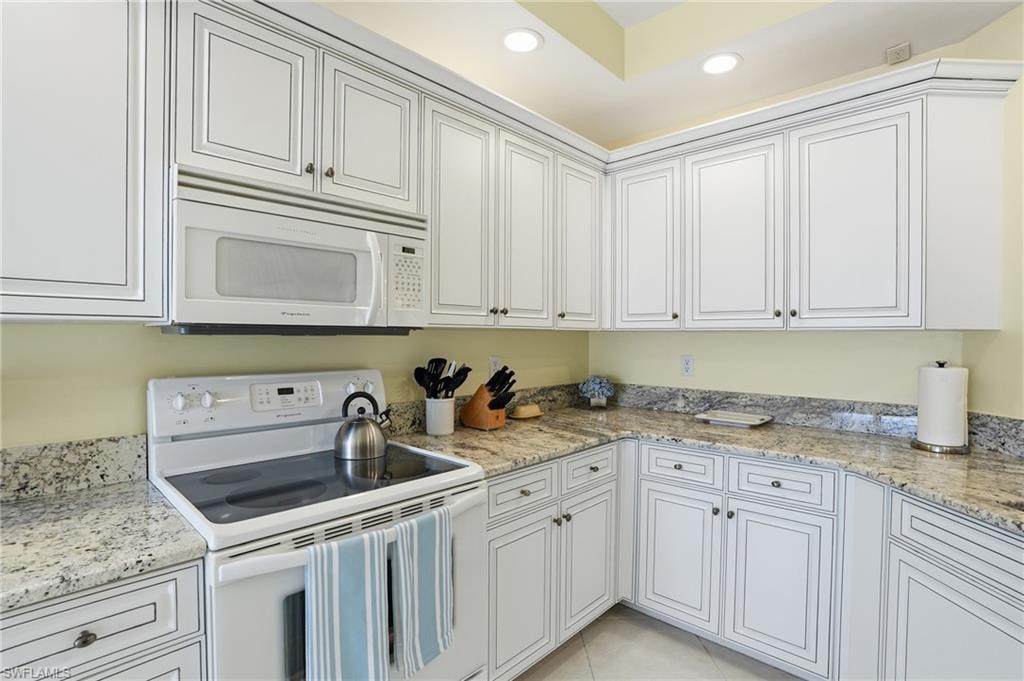 Kitchen with white appliances, light stone counters, white cabinets, recessed lighting and equipped with everything that you need for an enjoyable stay.