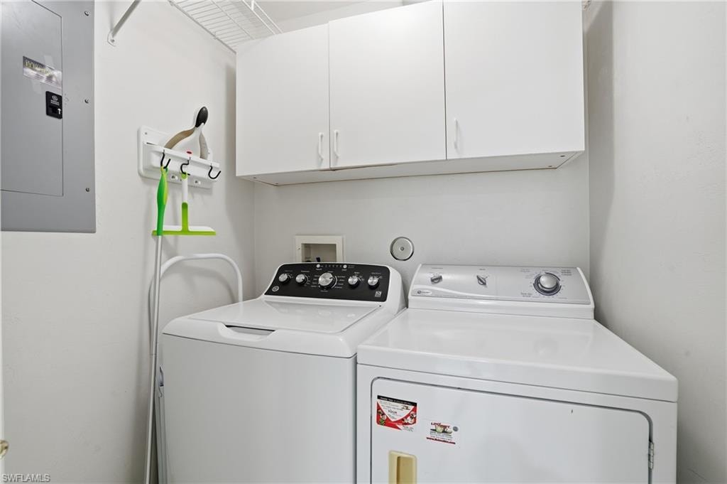 Washroom with electric panel, cabinet space, and washer and dryer
