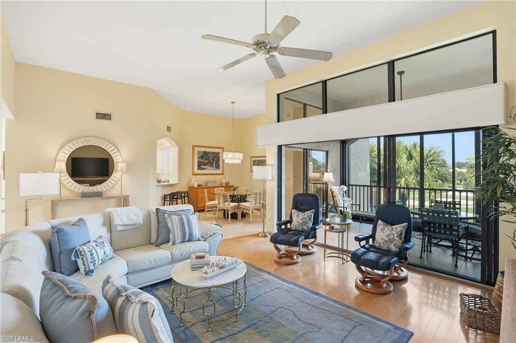 Living area with a ceiling fan, hardwood / wood-style floors, and a high ceiling