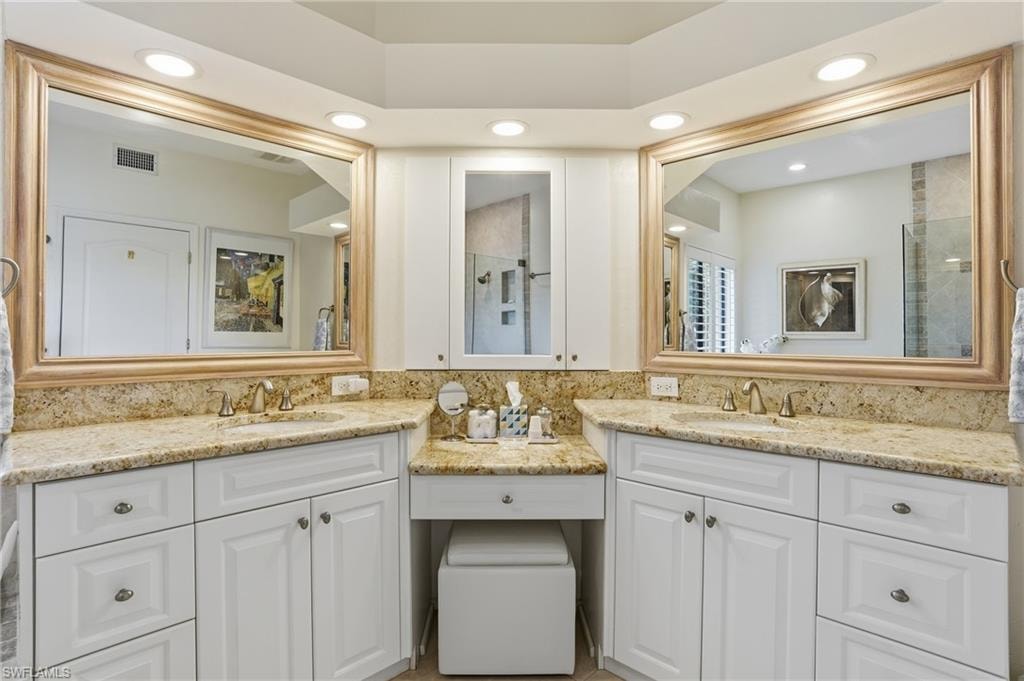 Full bath featuring two vanities, recessed lighting, and a shower with door