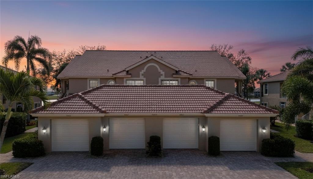 Mediterranean carriage home featuring a tiled roof, stucco siding, and garages