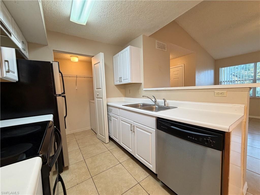 Kitchen with stainless steel appliances, a textured ceiling, white cabinets, light tile patterned flooring, and light countertops