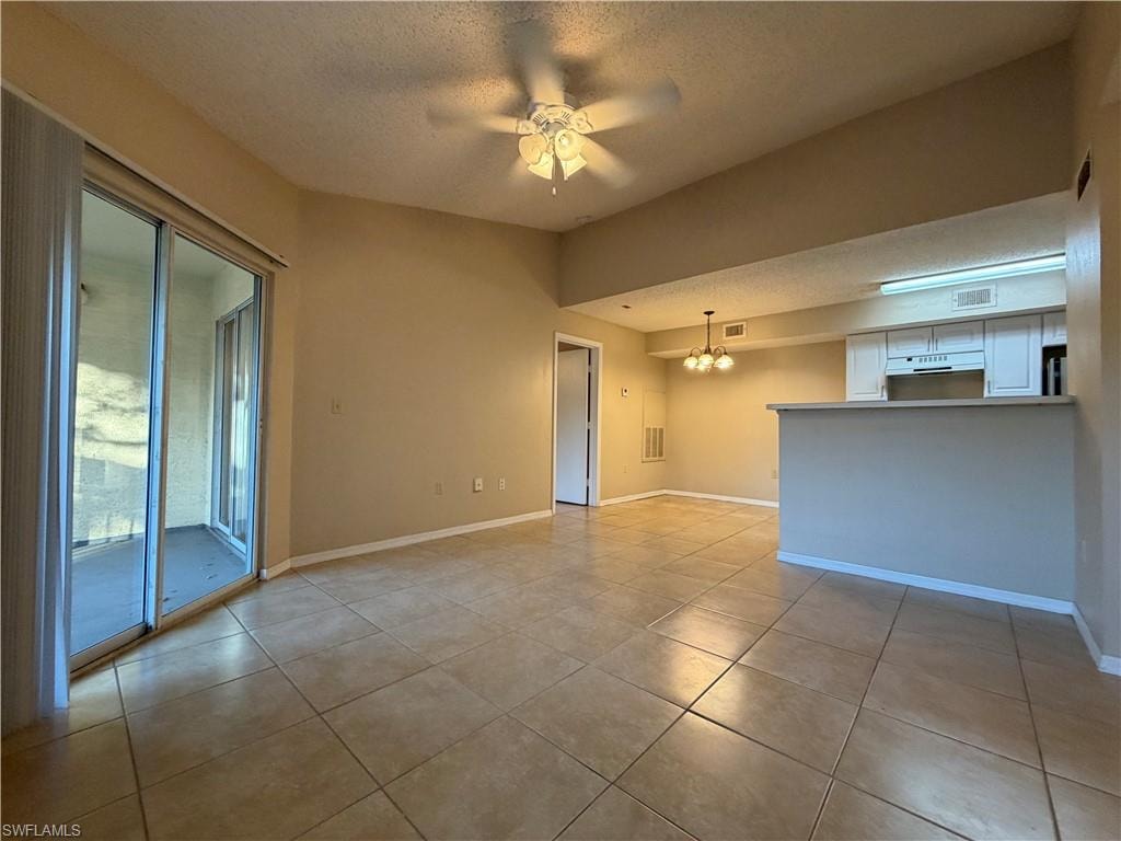 Unfurnished room with a textured ceiling, a chandelier, ceiling fan, and light tile patterned floors