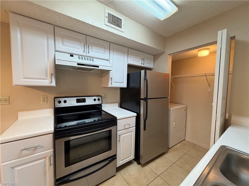 Kitchen featuring stainless steel appliances, a textured ceiling, under cabinet range hood, light countertops, and white cabinetry