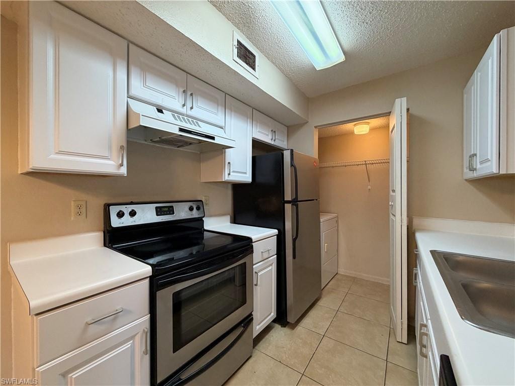 Kitchen featuring stainless steel appliances, under cabinet range hood, light countertops, a textured ceiling, and white cabinets