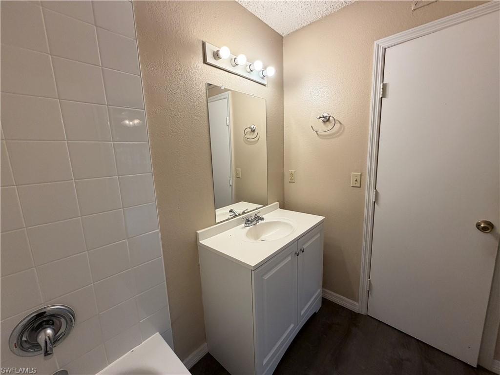 Bathroom featuring a textured wall and vanity