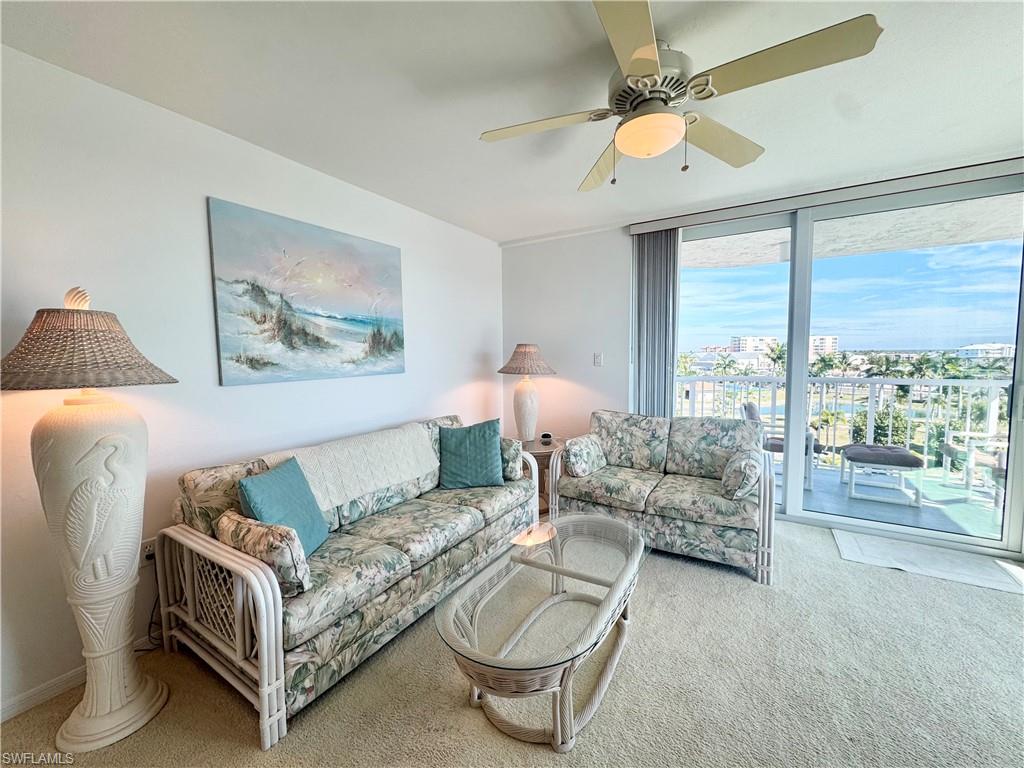 Carpeted living area featuring ceiling fan