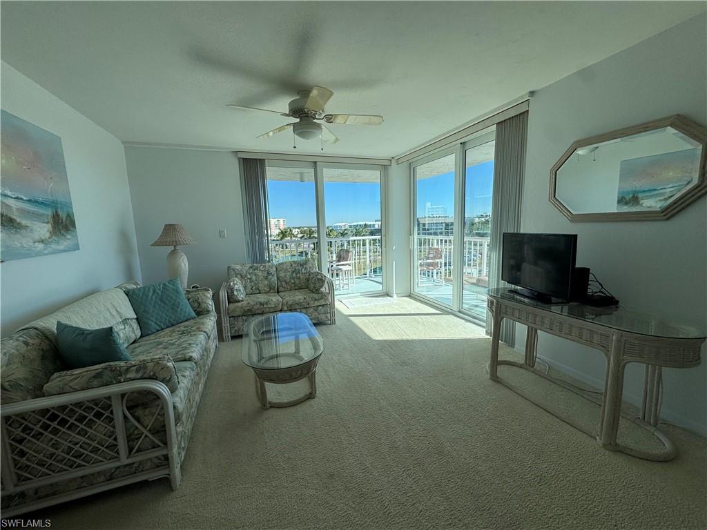 Living area with floor to ceiling windows, carpet, and ceiling fan