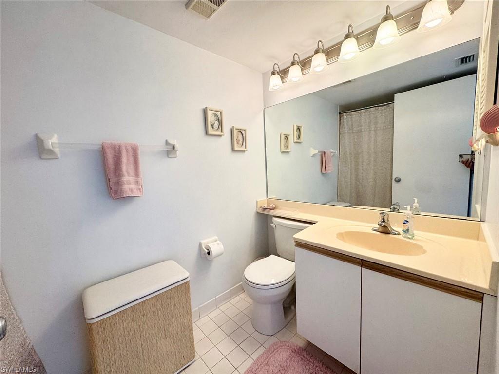 Bathroom with curtained shower, vanity, and light tile patterned flooring