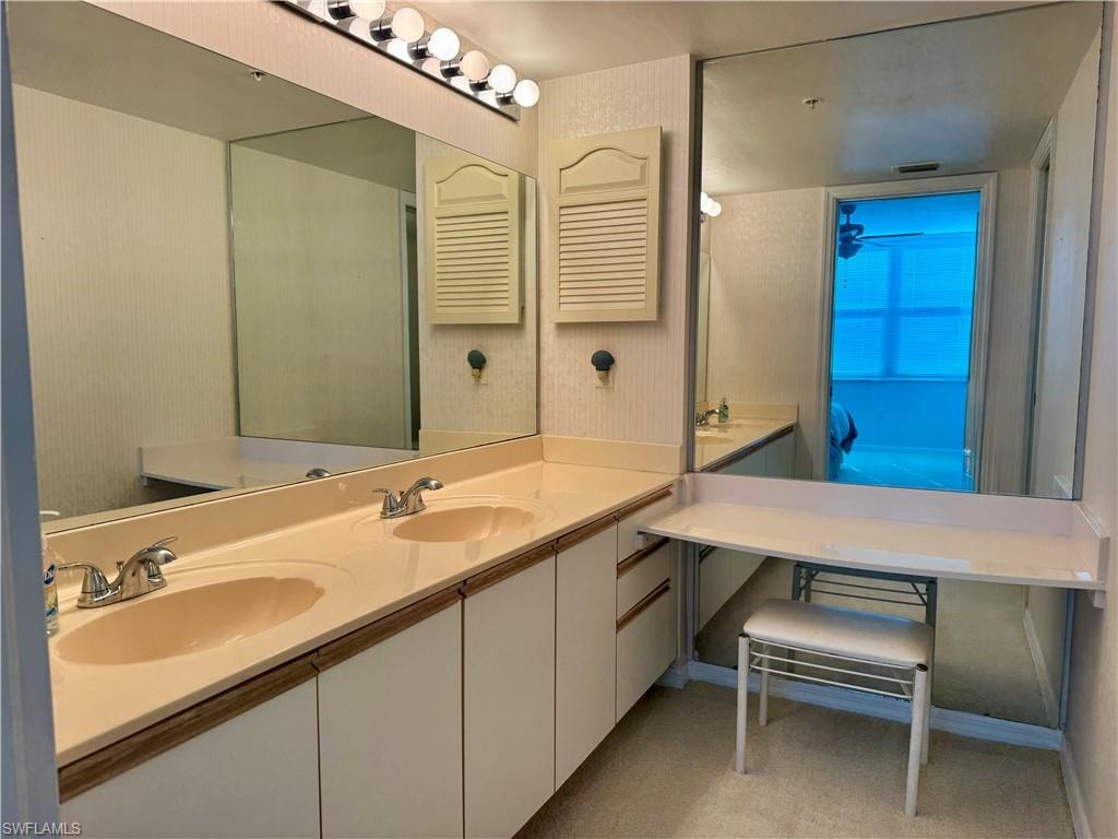 Bathroom with double vanity and light carpet
