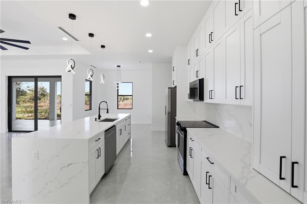 Kitchen featuring white cabinetry, light stone counters, stainless steel appliances, pendant lighting, and recessed lighting