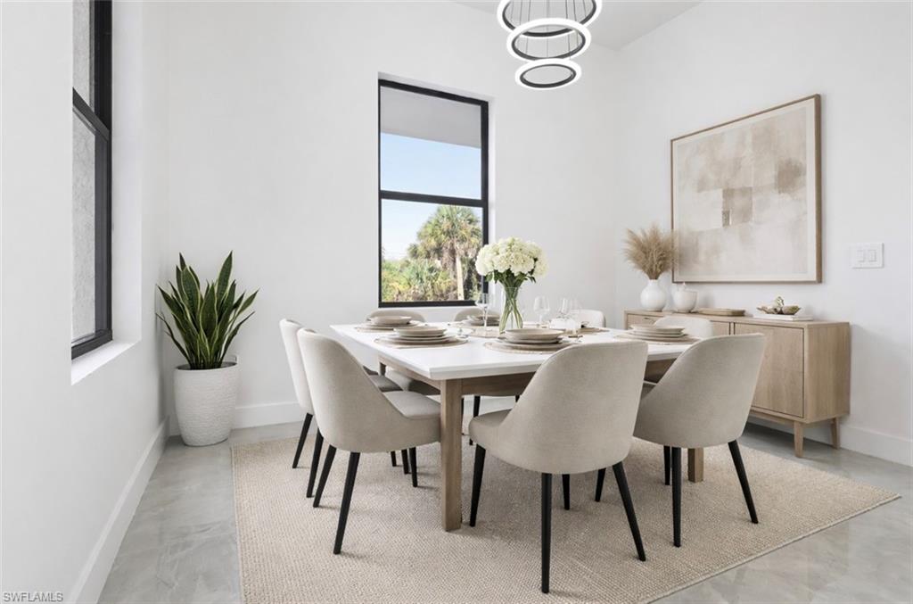 Dining space featuring hanging lights and finished concrete floors. Digitally staged