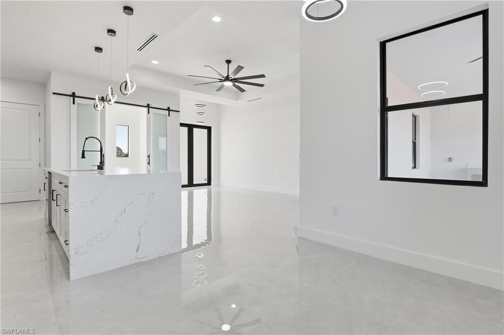 Kitchen featuring ceiling fan, pendant lighting, white cabinets, light stone countertops, and recessed lighting