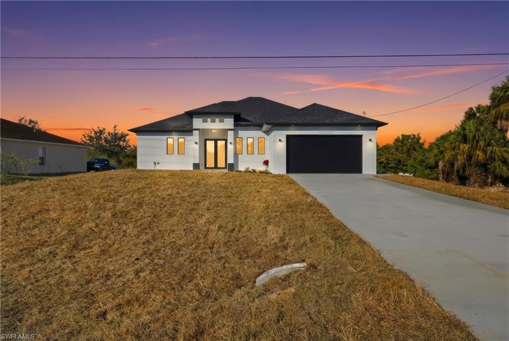 Prairie-style house featuring concrete driveway, an attached garage, stucco siding, and a front lawn