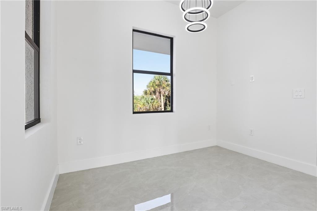 Unfurnished room with a chandelier and concrete floors