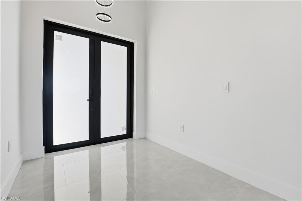 Unfurnished room featuring baseboards and french doors
