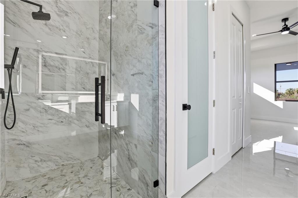 Bathroom featuring a marble finish shower and a ceiling fan