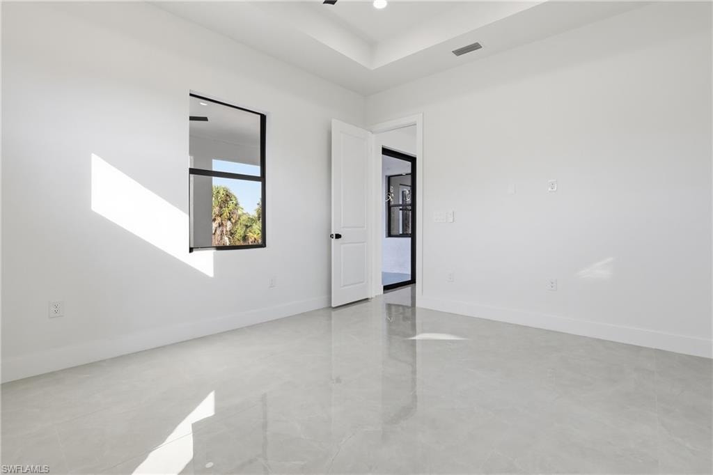 Unfurnished room featuring finished concrete flooring and a raised ceiling