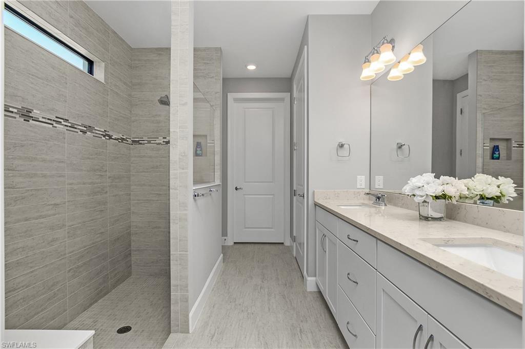 Primary ensuite bath with oversized walk-in shower, dual sinks, private water closet, linen closet, and spacious walk-in closet.