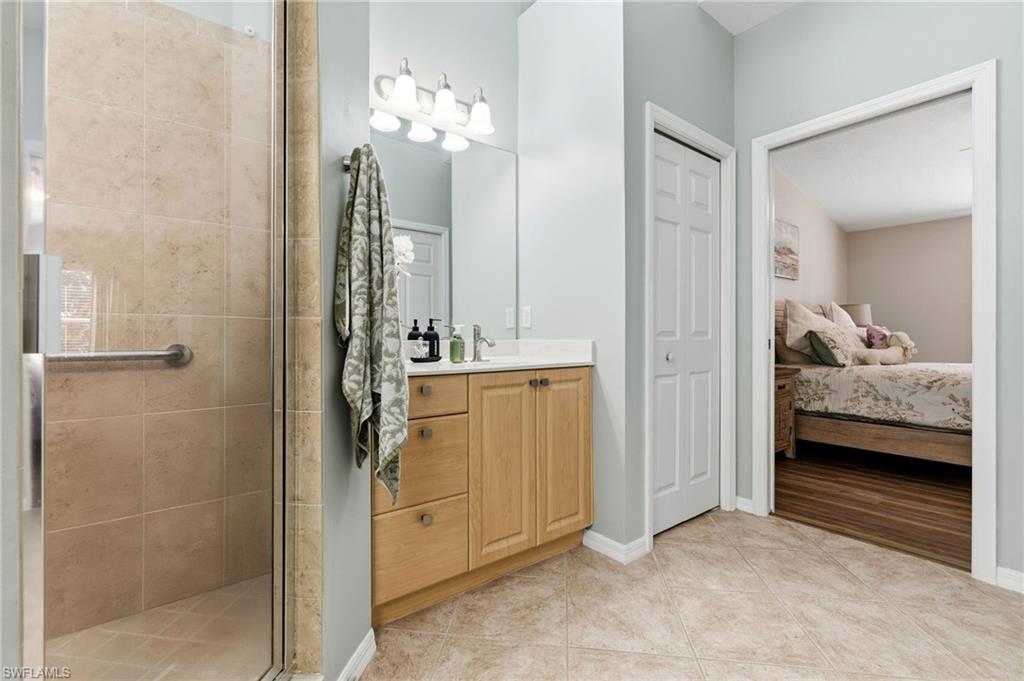 Ensuite bathroom featuring vanity, a shower stall, and light tile patterned flooring