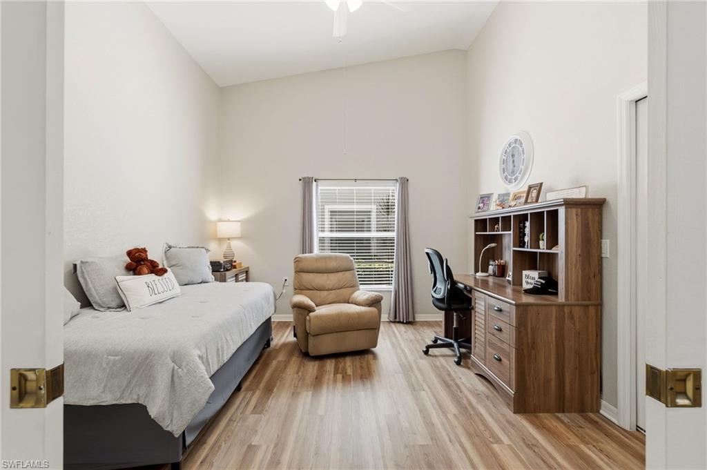 Bedroom featuring light wood-type flooring, high vaulted ceiling, a ceiling fan, and a desk