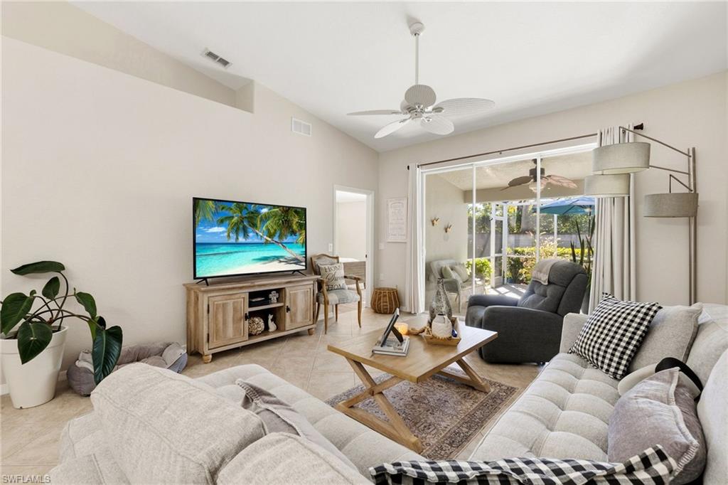 Living area with lofted ceiling, light tile patterned flooring, and ceiling fan