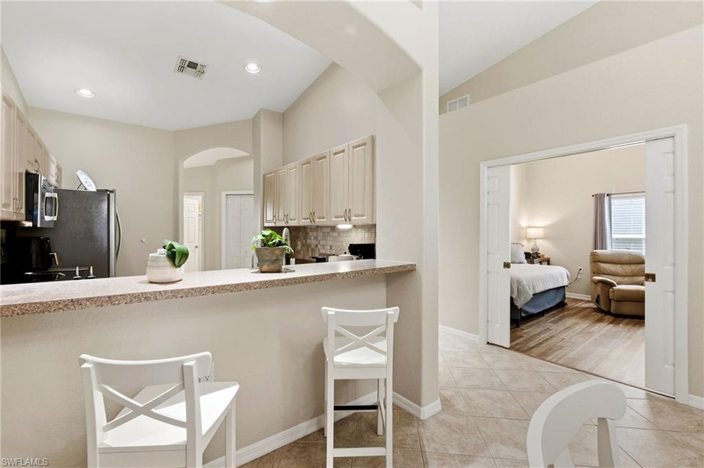 Kitchen with a breakfast bar area, backsplash, light countertops, vaulted ceiling, and arched walkways
