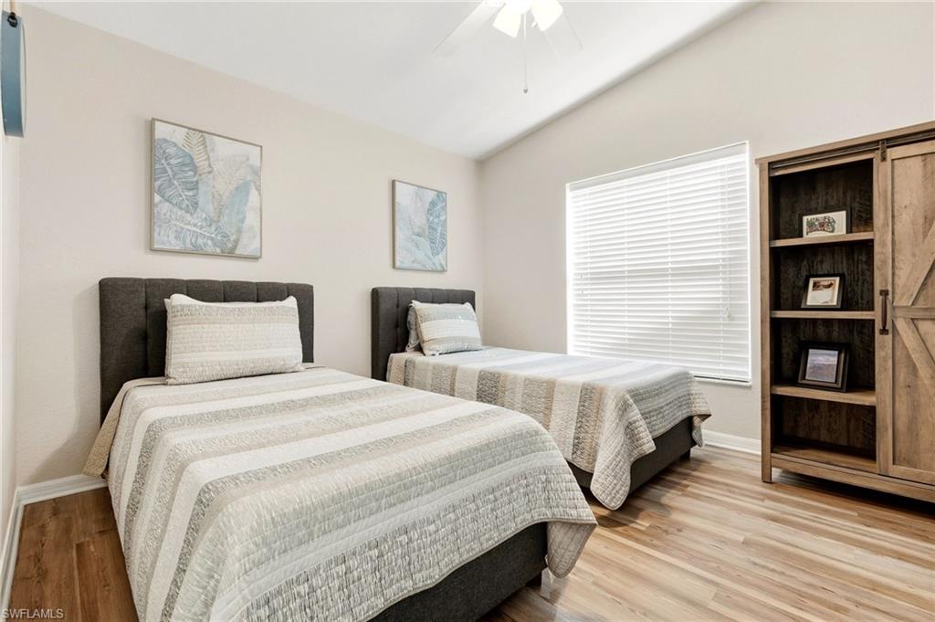 Bedroom with ceiling fan, lofted ceiling, and light wood-style floors